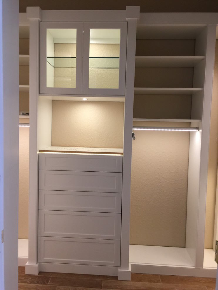 Ejemplo de armario vestidor unisex clásico renovado con armarios con paneles lisos, puertas de armario grises y suelo de madera en tonos medios