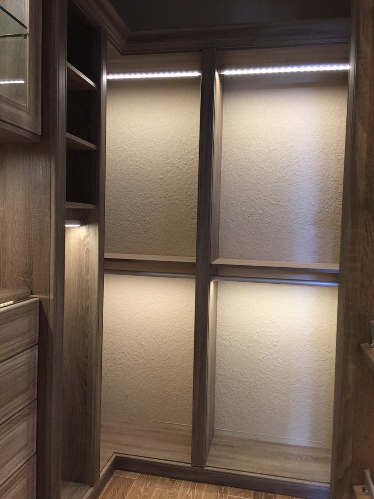 Modelo de armario vestidor unisex clásico renovado con armarios con paneles lisos, puertas de armario grises y suelo de madera en tonos medios