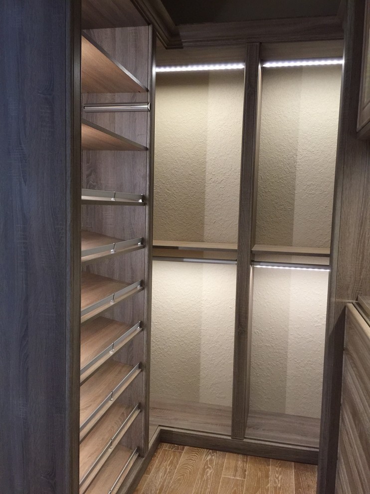 Foto de armario vestidor unisex tradicional renovado con armarios con paneles lisos, puertas de armario grises y suelo de madera en tonos medios