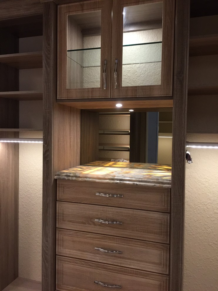 Modelo de armario vestidor unisex tradicional renovado con armarios con paneles lisos, puertas de armario grises y suelo de madera en tonos medios