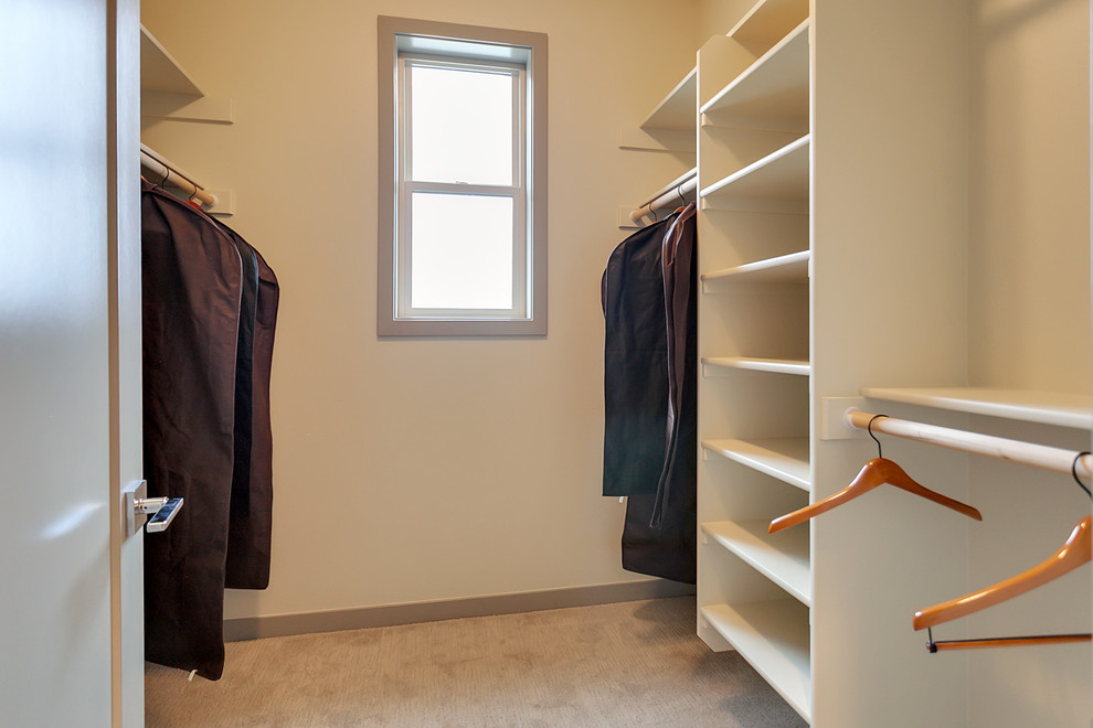 На фото: гардеробная комната среднего размера, унисекс в стиле неоклассика (современная классика) с серыми фасадами и ковровым покрытием