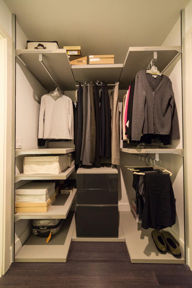 Imagen de armario vestidor unisex actual de tamaño medio con armarios con paneles lisos, puertas de armario grises y suelo de madera oscura