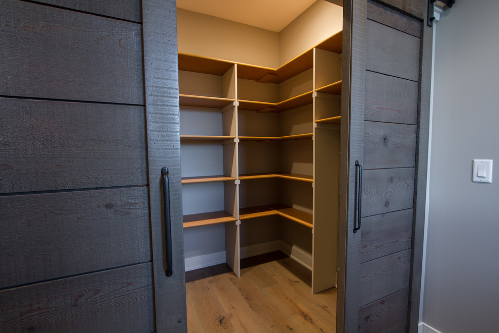 Large classic gender neutral walk-in wardrobe in Omaha with open cabinets and light hardwood flooring.