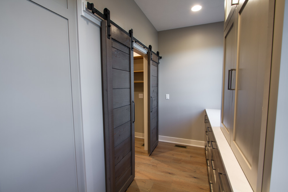 Inspiration for a large timeless gender-neutral light wood floor walk-in closet remodel in Omaha with open cabinets