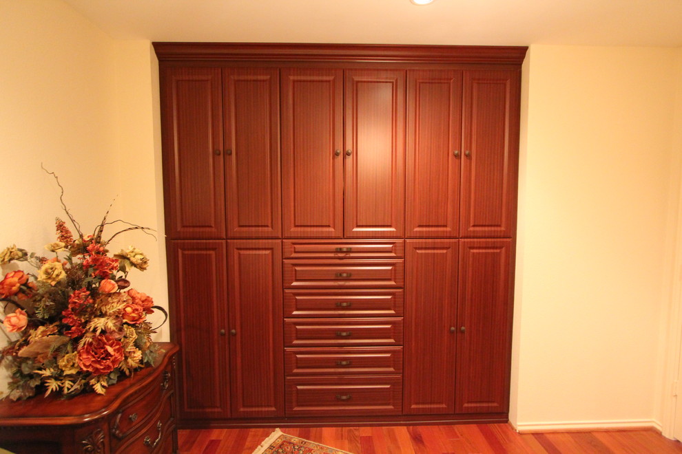 Modelo de armario unisex clásico de tamaño medio con armarios con paneles con relieve, puertas de armario de madera en tonos medios, suelo de madera oscura y suelo marrón