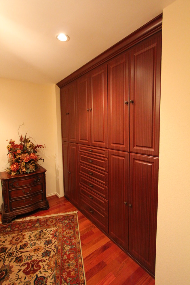 Reach-in closet - mid-sized traditional gender-neutral dark wood floor and brown floor reach-in closet idea in Dallas with raised-panel cabinets and dark wood cabinets