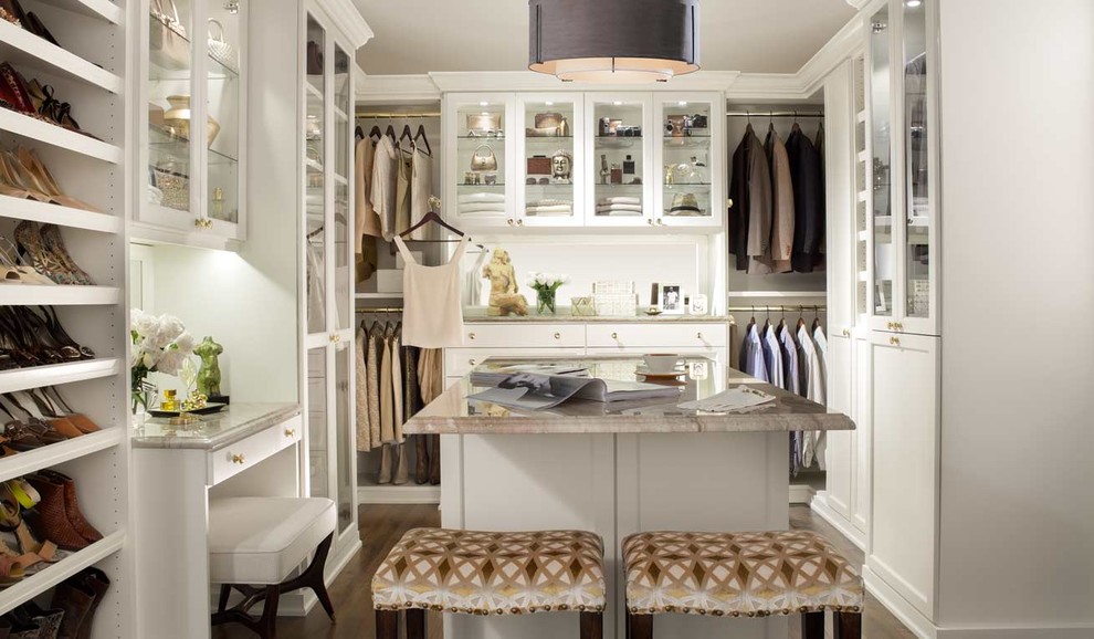 Inspiration for a large classic gender neutral dressing room in New York with glass-front cabinets, white cabinets and dark hardwood flooring.