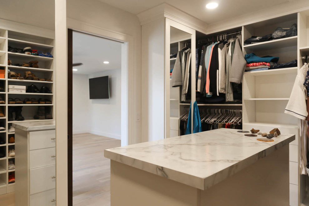 Diseño de armario vestidor unisex tradicional renovado de tamaño medio con armarios con paneles lisos, puertas de armario blancas, suelo de madera clara y suelo beige
