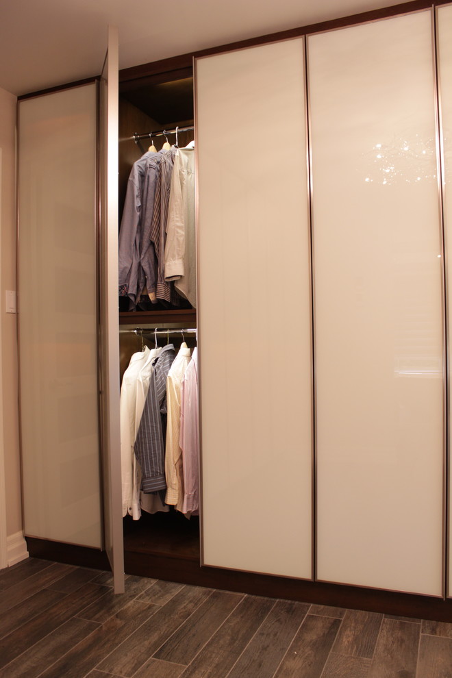Foto di un grande spazio per vestirsi unisex moderno con ante lisce, ante bianche e pavimento in legno massello medio