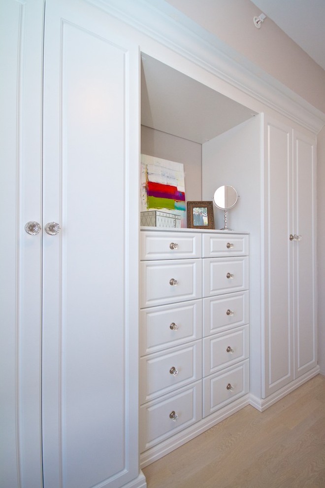 Ejemplo de armario de mujer clásico con armarios con paneles con relieve, puertas de armario blancas, suelo de madera clara y suelo beige