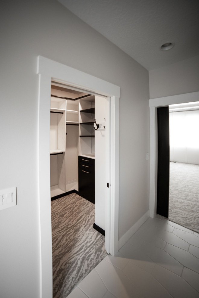Medium sized classic gender neutral walk-in wardrobe in Other with flat-panel cabinets, white cabinets, carpet and grey floors.