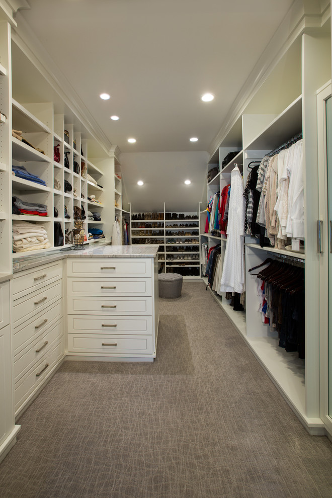 This is an example of a large contemporary walk-in wardrobe for women in DC Metro with raised-panel cabinets, white cabinets and carpet.