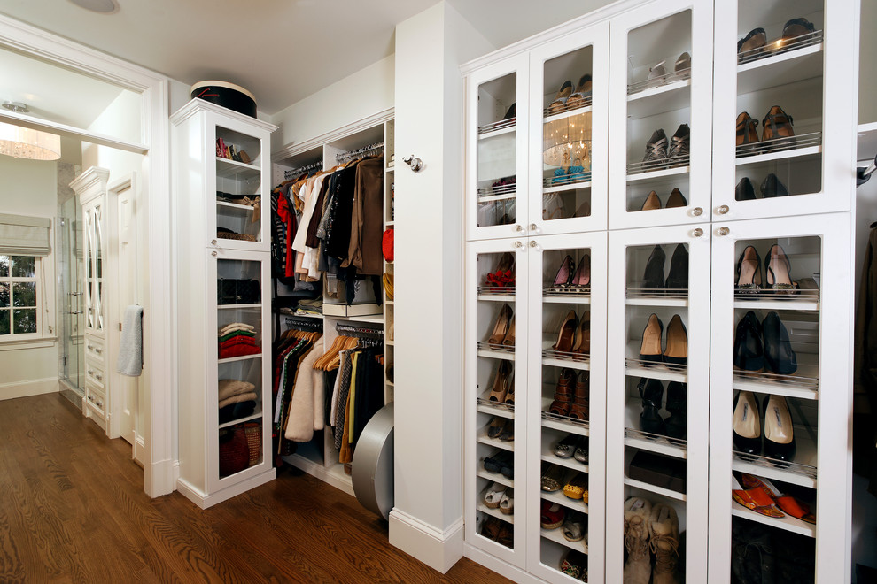 Example of a classic medium tone wood floor walk-in closet design in DC Metro with white cabinets