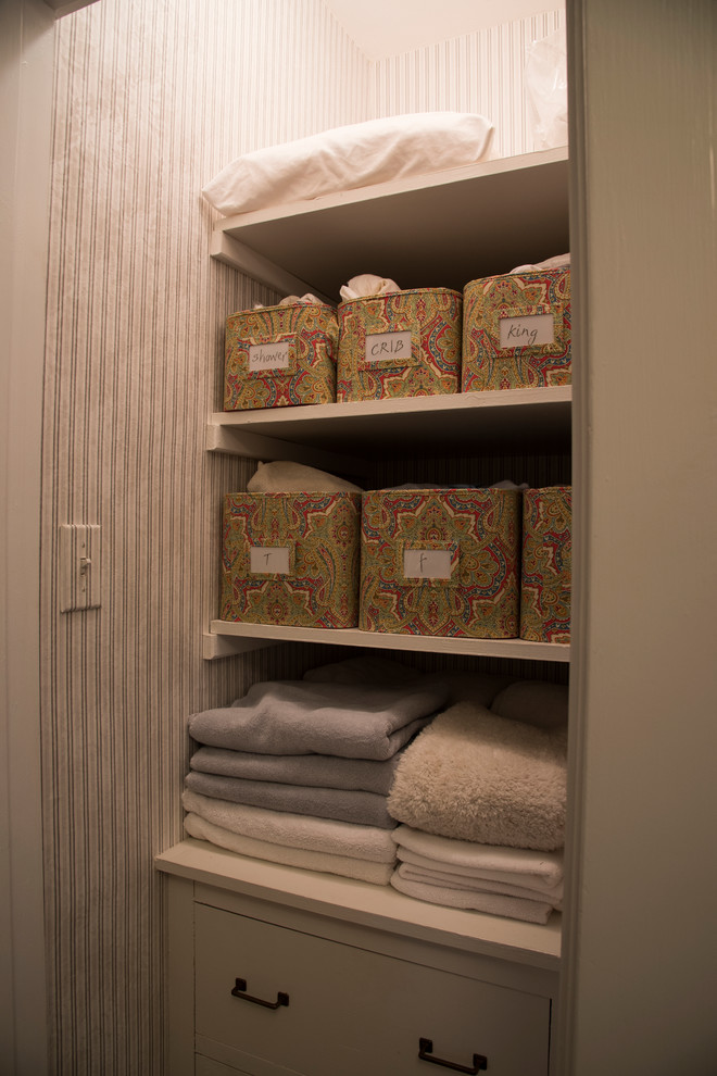 Diseño de armario unisex clásico pequeño con armarios con paneles lisos, puertas de armario blancas y suelo de madera en tonos medios