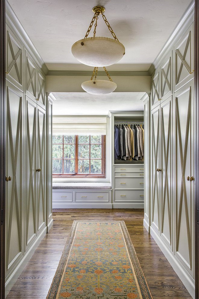 Diseño de armario vestidor tradicional con puertas de armario grises, suelo de madera oscura y suelo marrón
