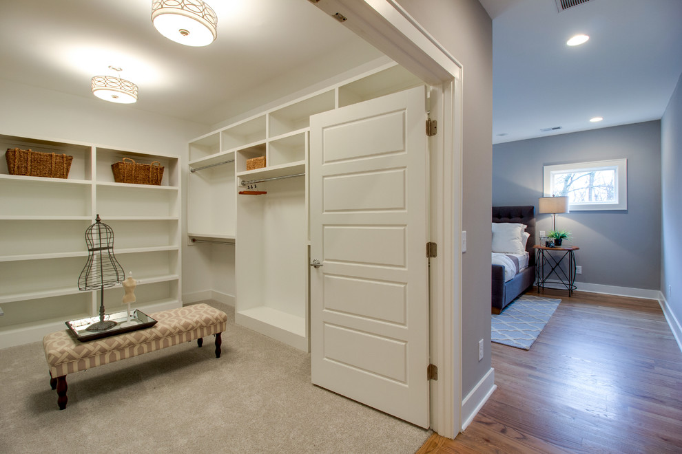 This is an example of an expansive classic gender neutral dressing room in Nashville with open cabinets, white cabinets, carpet and beige floors.