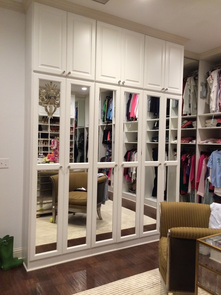Huge tuscan women's dark wood floor walk-in closet photo in New Orleans with white cabinets and raised-panel cabinets