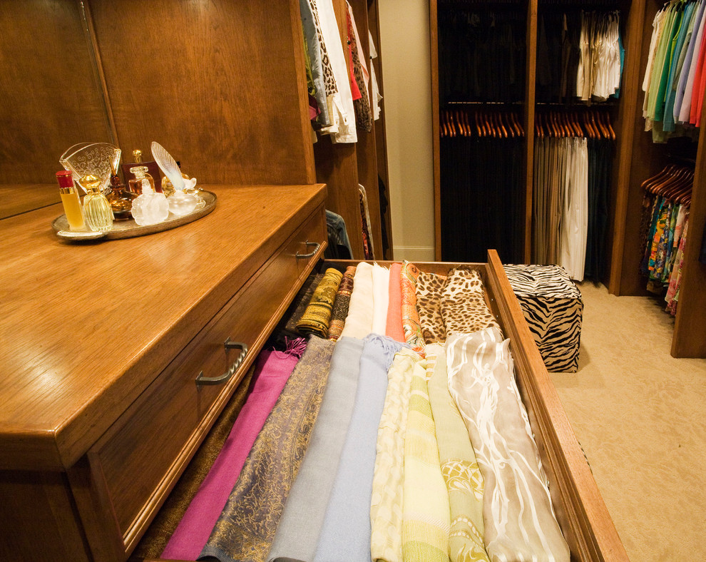 Walk-in closet - large traditional gender-neutral carpeted walk-in closet idea in Dallas with raised-panel cabinets and medium tone wood cabinets