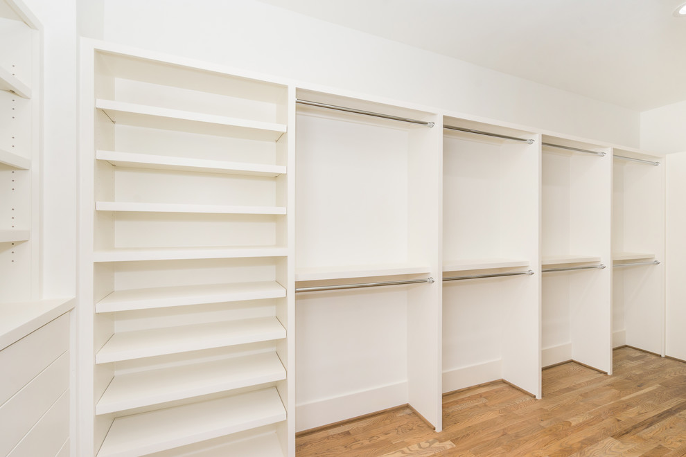 Imagen de vestidor unisex clásico renovado grande con armarios abiertos, puertas de armario blancas y suelo de madera clara