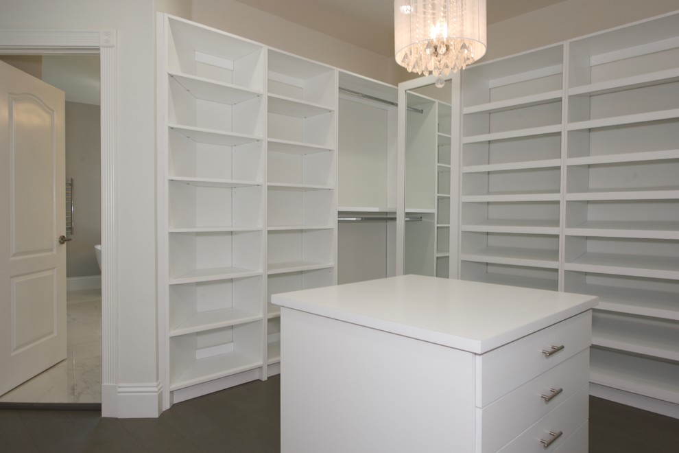 Imagen de armario vestidor unisex clásico renovado grande con armarios con paneles lisos, puertas de armario blancas, suelo de madera en tonos medios y suelo gris