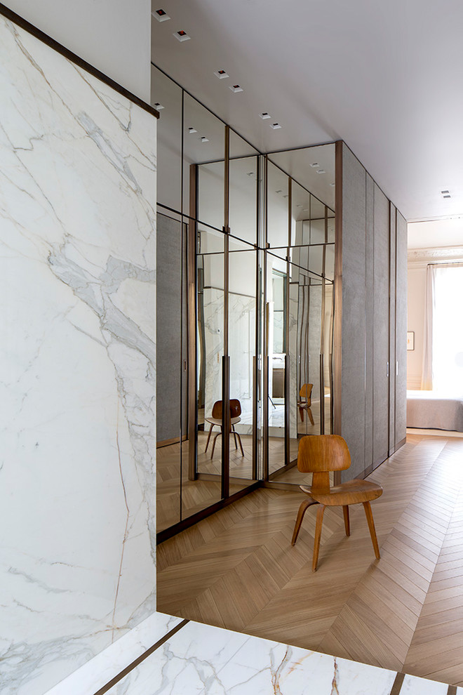 This is an example of a medium sized contemporary standard wardrobe for men in Paris with beaded cabinets, light hardwood flooring and beige floors.