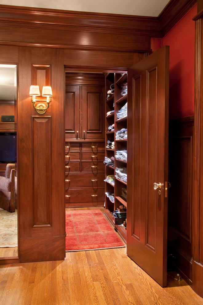 Ejemplo de armario vestidor de hombre clásico grande con armarios con paneles con relieve, puertas de armario de madera oscura y suelo de madera en tonos medios
