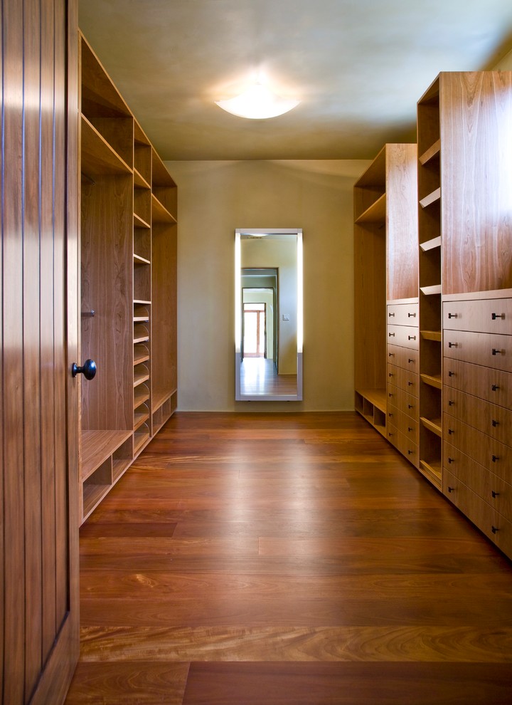 Foto de vestidor tropical extra grande con armarios con paneles con relieve, puertas de armario de madera en tonos medios, suelo de madera oscura y suelo marrón