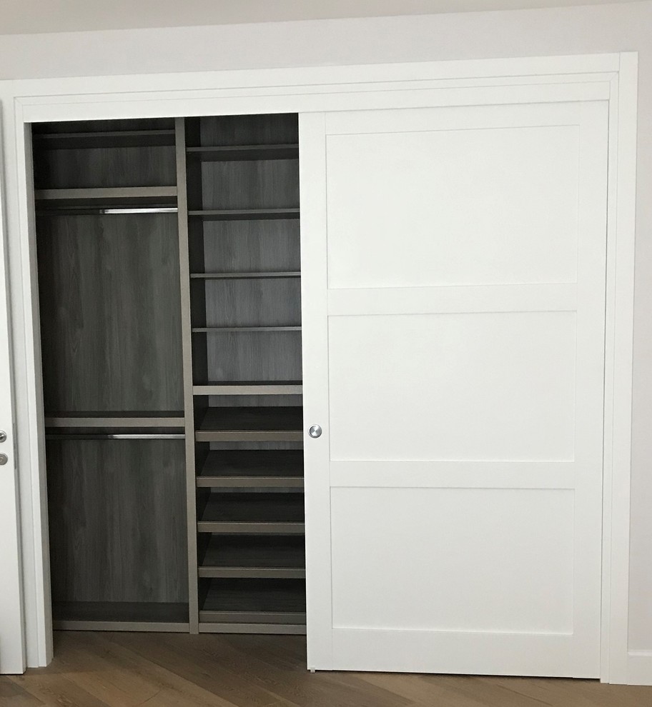 Exemple d'un petit placard dressing moderne neutre avec un placard à porte plane et des portes de placard blanches.