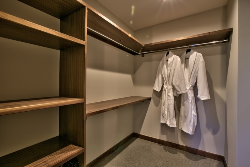 Diseño de armario vestidor unisex actual de tamaño medio con armarios abiertos, puertas de armario de madera oscura y moqueta
