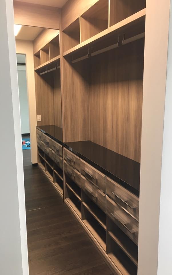 This is an example of a large contemporary gender neutral walk-in wardrobe in Miami with raised-panel cabinets, medium wood cabinets, dark hardwood flooring and brown floors.