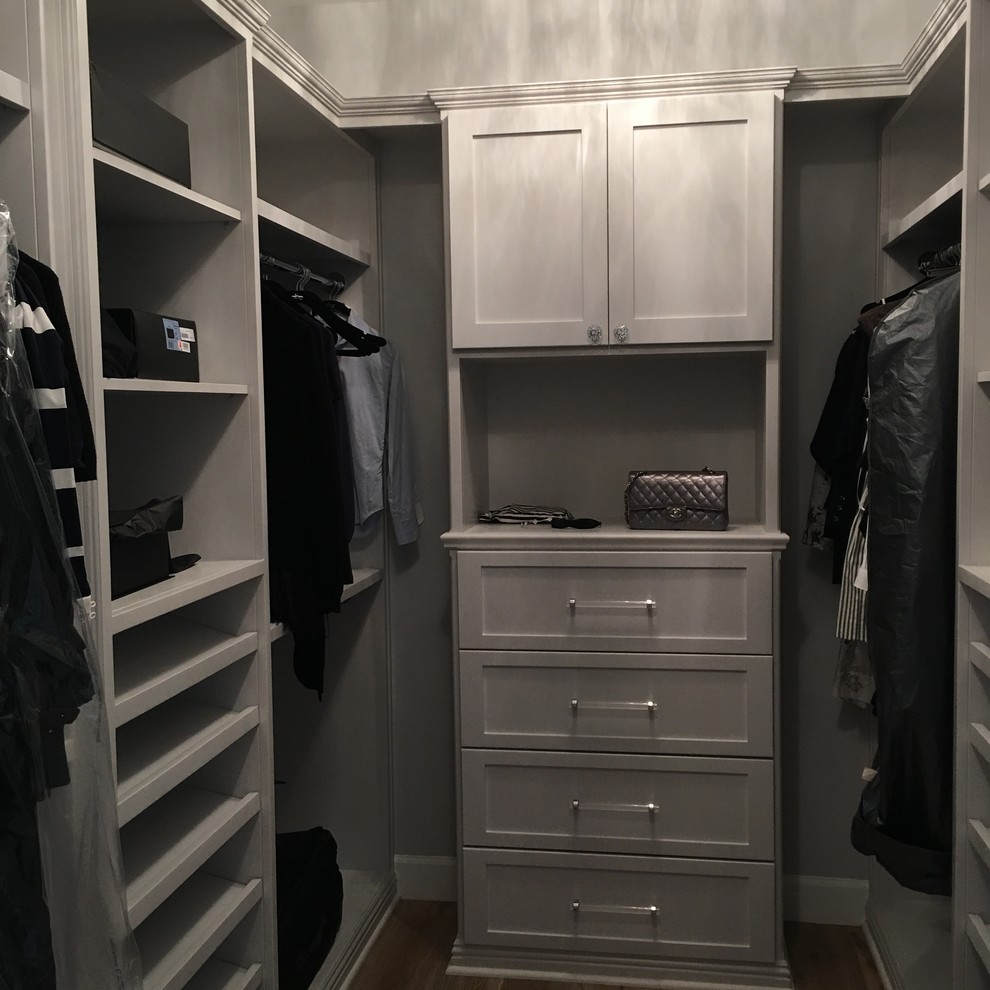 Medium sized modern walk-in wardrobe for women in Orange County with shaker cabinets, grey cabinets and medium hardwood flooring.