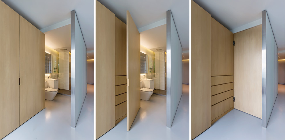 Diseño de armario unisex contemporáneo pequeño con armarios con paneles lisos, suelo de cemento y puertas de armario de madera clara