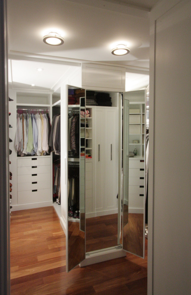 Walk-in closet - mid-sized transitional gender-neutral medium tone wood floor walk-in closet idea in New York with flat-panel cabinets and white cabinets