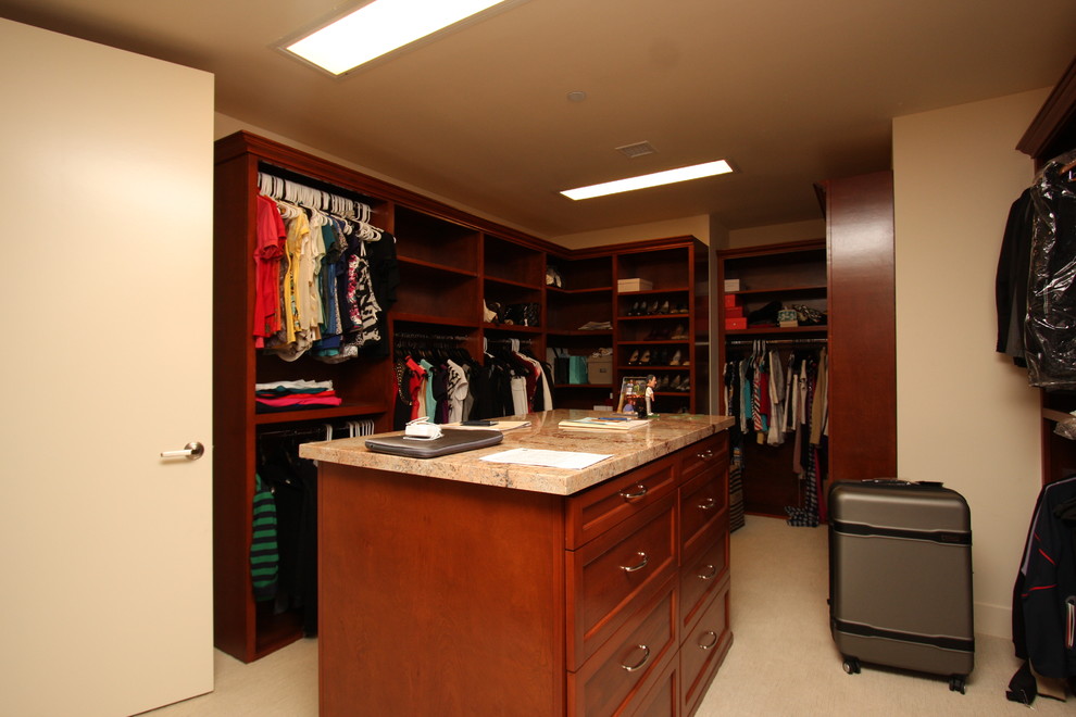 Ejemplo de armario vestidor unisex tradicional grande con armarios con paneles con relieve, puertas de armario de madera oscura y moqueta