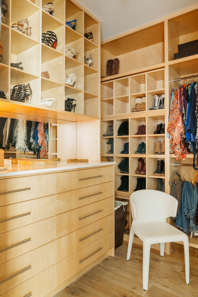 This is an example of a contemporary gender neutral walk-in wardrobe in Houston with open cabinets, light wood cabinets, light hardwood flooring and beige floors.