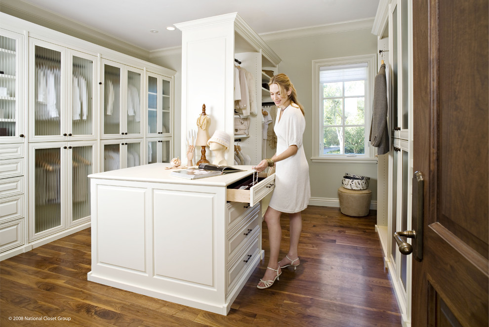 This is an example of a large classic gender neutral walk-in wardrobe in San Francisco with raised-panel cabinets, white cabinets, medium hardwood flooring and brown floors.