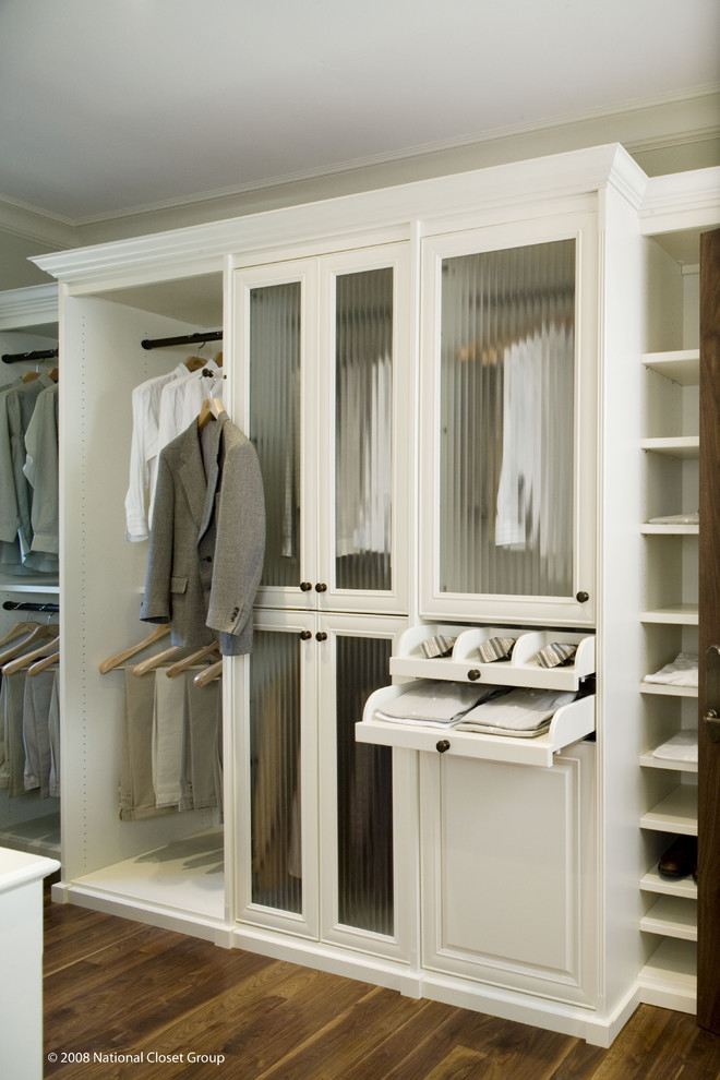 Foto de armario vestidor unisex tradicional grande con armarios con paneles con relieve, puertas de armario blancas, suelo de madera en tonos medios y suelo marrón