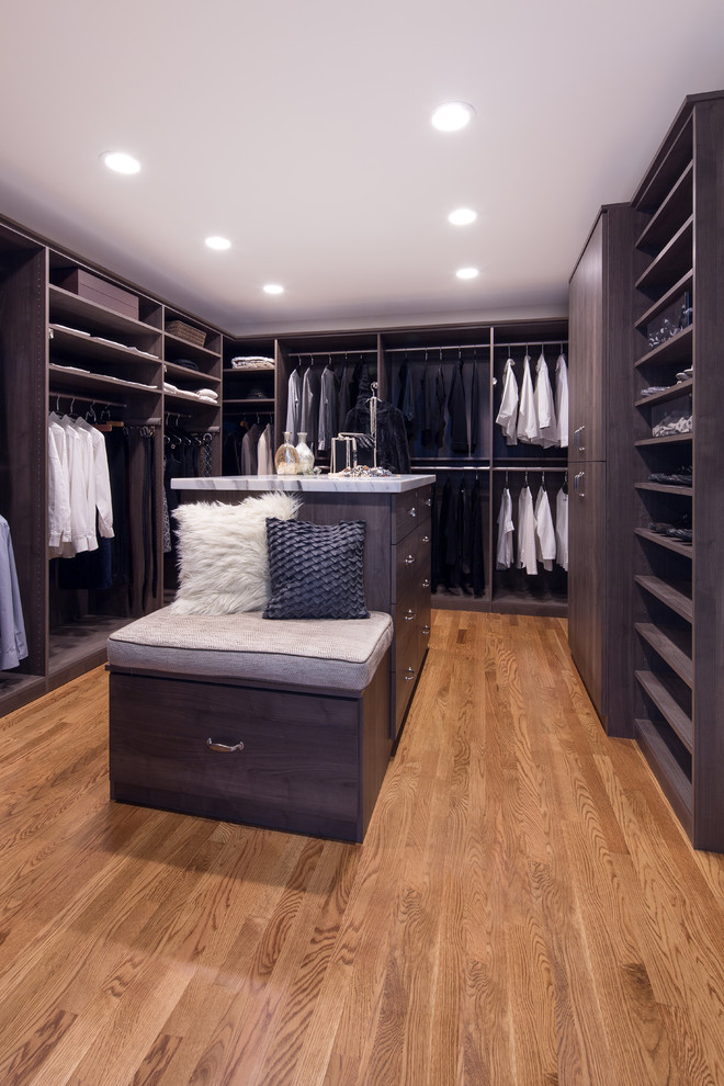 Modelo de armario vestidor unisex actual grande con armarios con paneles lisos, puertas de armario grises y suelo de madera en tonos medios