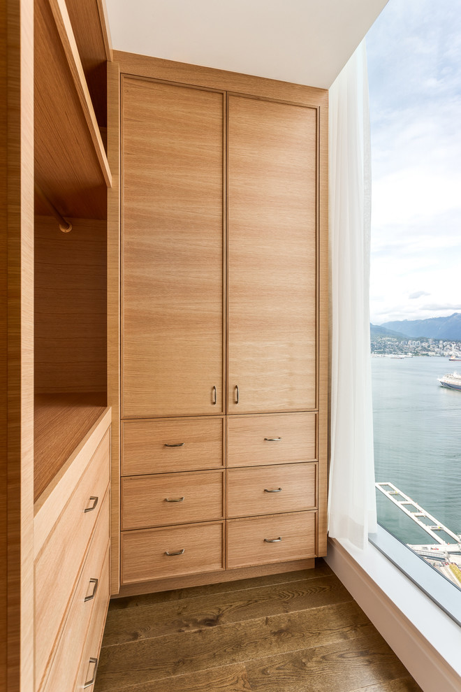 Ejemplo de armario vestidor unisex contemporáneo extra grande con armarios con rebordes decorativos, puertas de armario de madera oscura y suelo de madera clara