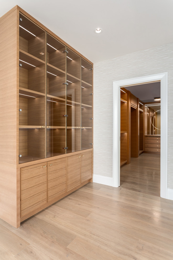Ejemplo de armario vestidor unisex contemporáneo extra grande con puertas de armario de madera oscura y suelo de madera clara
