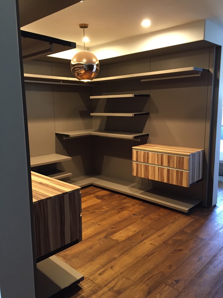 Modelo de armario vestidor unisex minimalista de tamaño medio con armarios con paneles lisos, puertas de armario de madera clara, suelo de madera oscura y suelo marrón