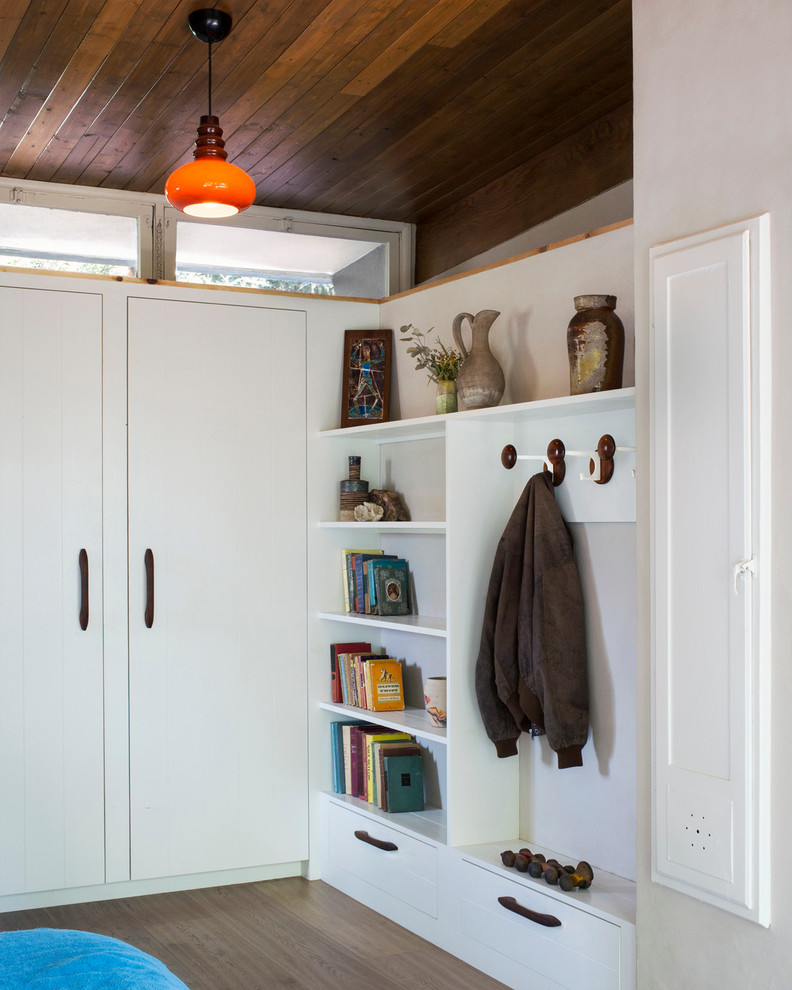 Inspiration for a small midcentury standard wardrobe for men in Los Angeles with open cabinets, white cabinets, light hardwood flooring and exposed beams.