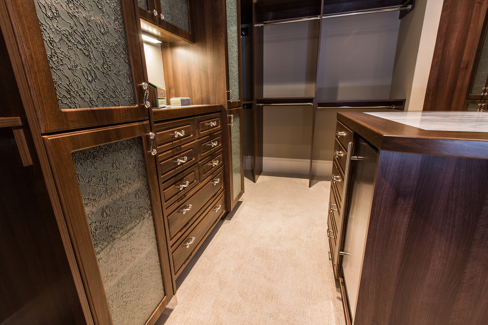 Inspiration for an expansive traditional walk-in wardrobe for women in San Diego with raised-panel cabinets, dark wood cabinets and carpet.