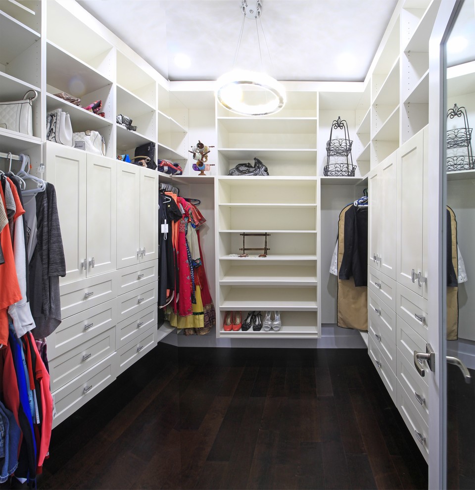 Пример оригинального дизайна: большая гардеробная комната унисекс в стиле неоклассика (современная классика) с фасадами в стиле шейкер, белыми фасадами, темным паркетным полом и коричневым полом