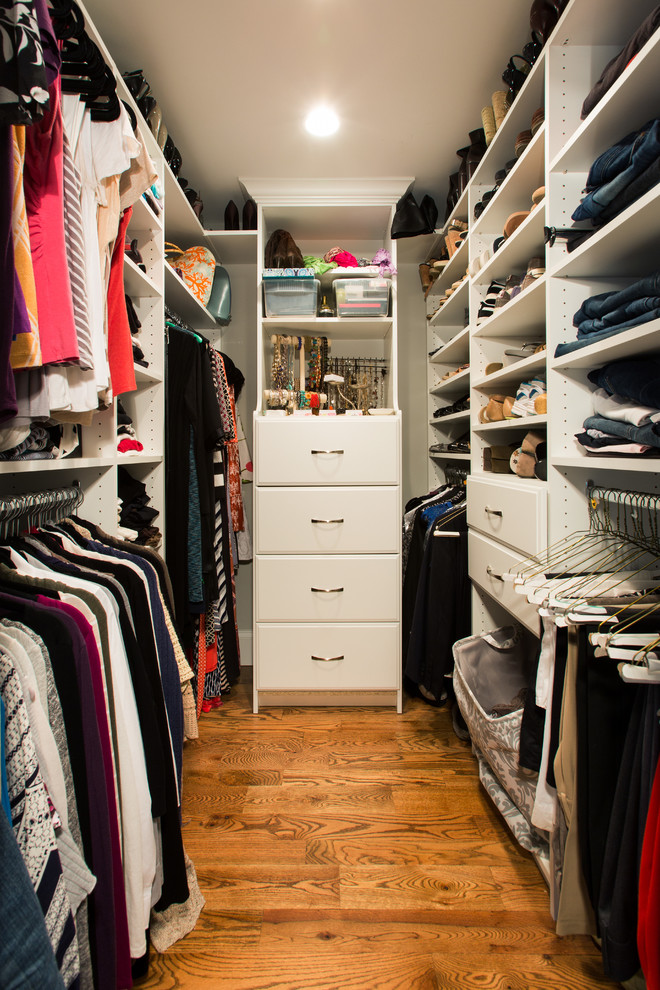 Ejemplo de armario vestidor unisex tradicional con armarios con paneles lisos, puertas de armario blancas y suelo de madera en tonos medios