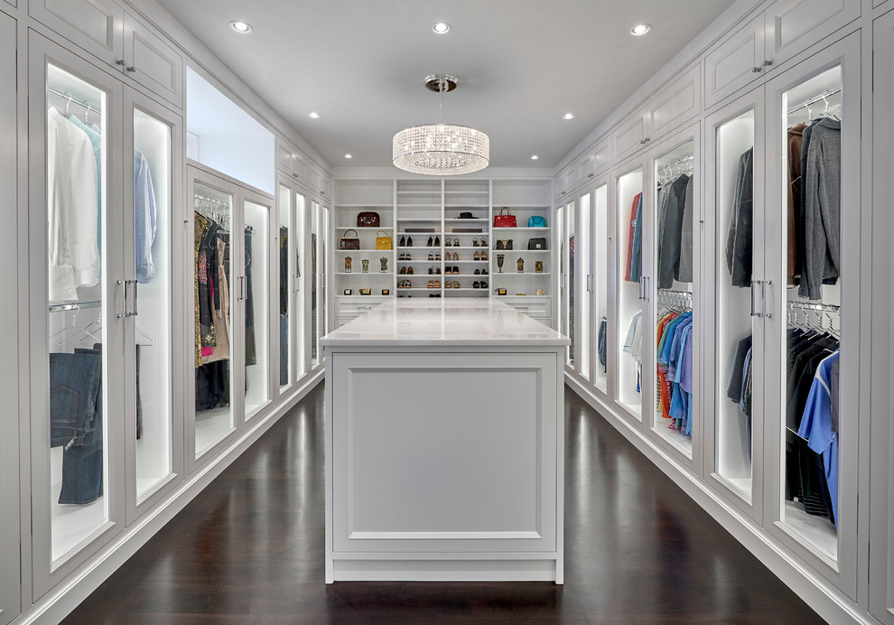 Idée de décoration pour un dressing room méditerranéen neutre avec des portes de placard blanches, parquet foncé, un sol marron et un placard à porte vitrée.