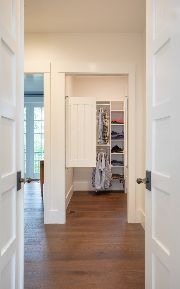 Ejemplo de armario vestidor unisex clásico de tamaño medio con suelo de madera en tonos medios y suelo marrón