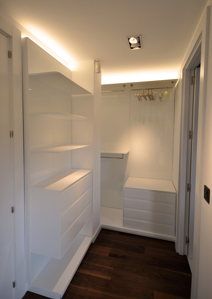 Idée de décoration pour un dressing minimaliste de taille moyenne et neutre avec un placard à porte plane, des portes de placard blanches et parquet foncé.