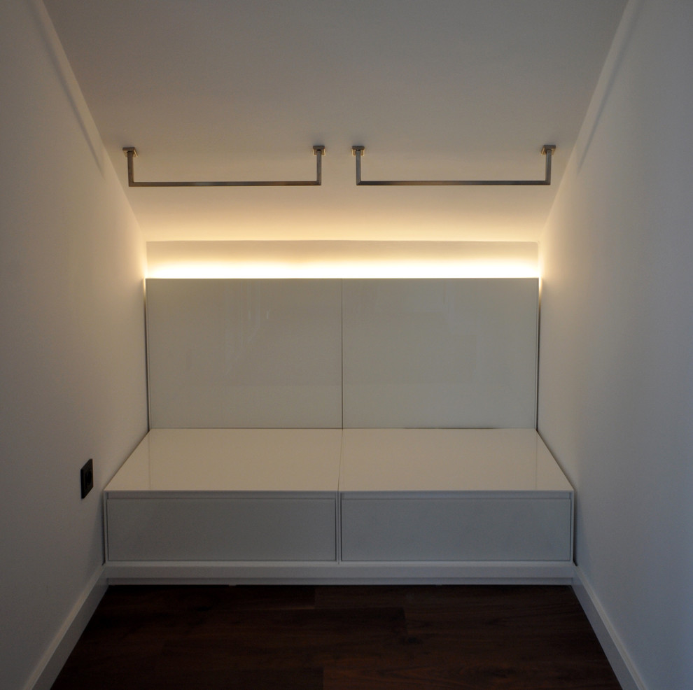 Foto de armario vestidor unisex contemporáneo de tamaño medio con armarios con paneles lisos, puertas de armario blancas y suelo de madera oscura