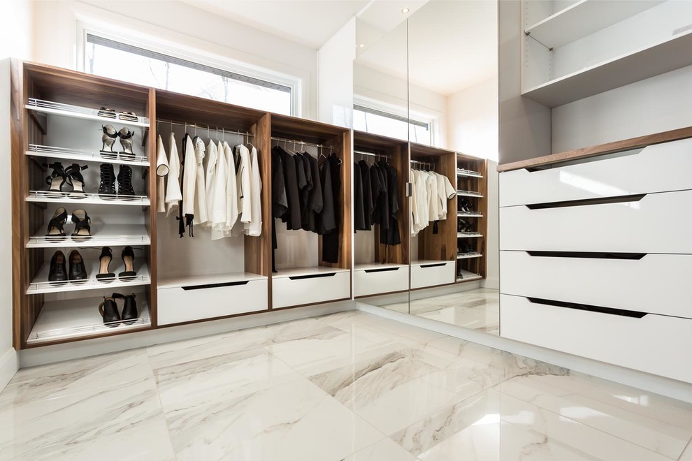 Imagen de armario vestidor unisex moderno grande con armarios con paneles lisos, puertas de armario de madera oscura, suelo de mármol y suelo blanco